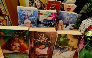 Na biurku są wyłożone na podp&oacute;rkach książki o tematyce świątecznej