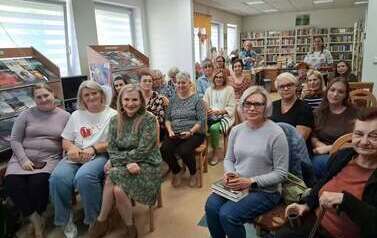 Wszystkie krzesła w bibliotece zajęte przez gości przybyłych na spotkanie autorskie