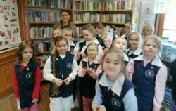 Dzieci stoją w grupie razem z Panią bibliotekarką w bibliotece w Borzechowie