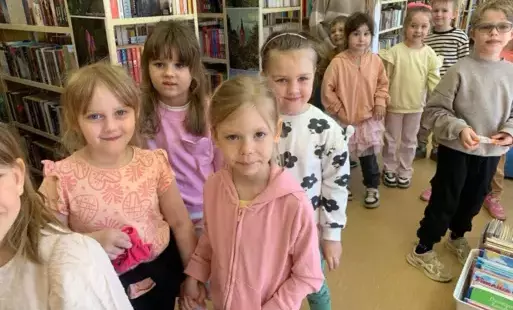 Dzieci stoją w parach w bibliotece przygotowując się do wyjścia
