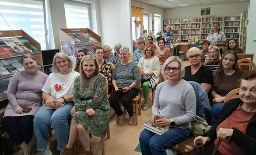 Wszystkie krzesła w bibliotece zajęte przez gości przybyłych na spotkanie autorskie